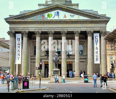 Glasgow, Schottland, Vereinigtes Königreich, 18. Juni 2023. Die Besucherzahlen in der CUT & RUN The Banksy-Ausstellung an der Statue des Herzog von Wellington mit dem Zapfenkopf vor dem GOMA, der Galerie für moderne Kunst, wurden heute eröffnet. Credit Gerard Ferry/Alamy Live News Stockfoto