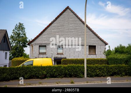 Ein gelbes Auto steht hinter einer Hecke vor einem grauen Ziegelhaus in Gevelsberg-Silschede, Nordrhein-Westfalen, Deutschland. Ein gelbes Auto Stand Tipp Stockfoto