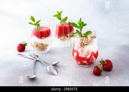 Gesundes, leckeres Frühstück, Gläser mit Müsli und Joghurt und ErdbeerSmoothie Stockfoto