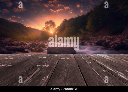 Magischer Sonnenaufgang über einem schnell fließenden Bergfluss mit leerer Holzbalken-Brücke. Natürliche Vorlagenlandschaft. Stockfoto