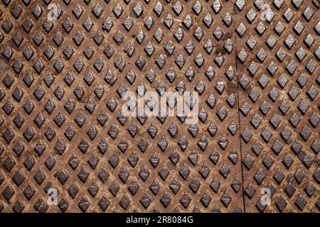 Rostig verschlissene Trittplatte mit Diamantmuster für Rutschfestigkeit. Altes Blech mit einem Rhombus-Muster, industrieller Hintergrund Stockfoto