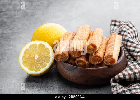 Hausgemachte Zitronenmarmelade mit Stäbchen in Holzschüssel auf grauem Hintergrund Stockfoto