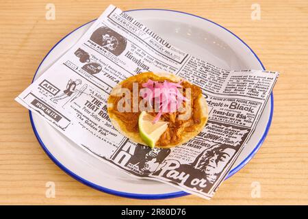 Gebratener Fisch und Pommes Frites auf einem Teller mit Zeitung auf einem Holztisch Stockfoto