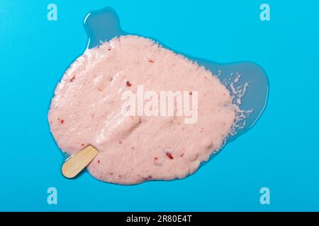Eis am Stiel mit geschmolzenem Erdbeergeschmack von oben auf blauem Hintergrund Stockfoto