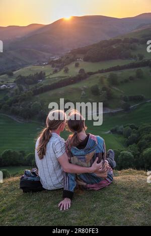 Ein junges Paar, das den Sonnenuntergang von Castell Dinas Brân, Llangollen, Wales aus beobachtet Stockfoto