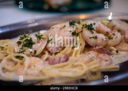 Weißwein, Sahne, Garnelen und Spaghetti mit Speck, serviert auf einem Teller Stockfoto