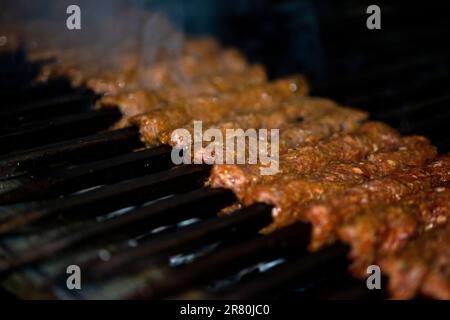 Scharfe Seekh-Kebabs werden auf brennender Holzkohle gegrillt, während einer Dinnerparty am Abend Stockfoto