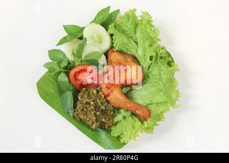 Galangal gebratenes Hähnchen, Sambal, Tomate, Gurke, Basilikum, Salat. Indonesische Küche auf Bananenblatt-Teller. Gastronomie-Fotografie auf weißem Hintergrund Stockfoto