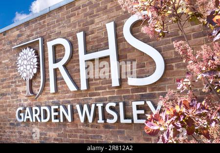 Rechts: Garden Wisley Eingangsschild. Modernes Schild eingerahmt von Cotinus „Candy Floss“ am Eingang zum RHS Horticultural Garden Wisley Surrey UK Stockfoto