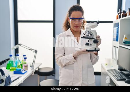 Junge hispanische Frau, die im Wissenschaftlerlabor arbeitet, skeptisch und nervös, runzelte die Stirn wegen des Problems. Negative Person. Stockfoto