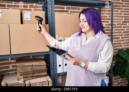 Junge, wunderschöne, übergroße Frau, E-Commerce-Mitarbeiter, die im Büro ein Paket scannen und Dokumente lesen Stockfoto