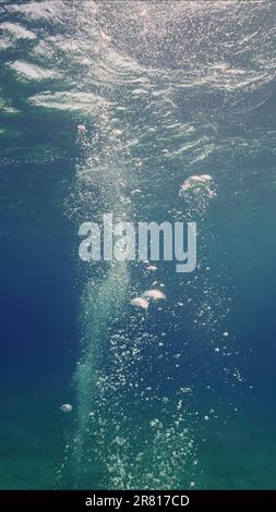 Luftblasenbewegungen steigen in blauem Wasser an die Oberfläche auf. Sonnenstrahlen und Luftblasen unter Wasser, Rotes Meer, Ägypten Stockfoto