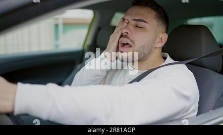 Junger latino, müde, Auto zu fahren und auf der Straße zu gähnen Stockfoto