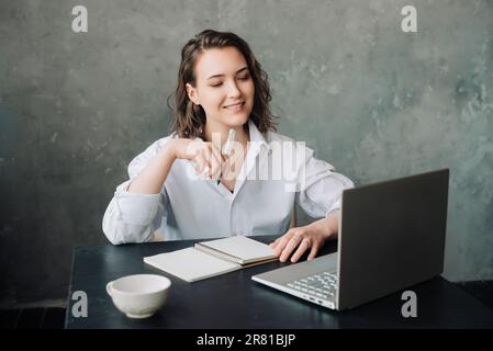Befähigung zum Fernunterricht: Frau, die sich mit einem Notebook zu Hause für E-Learning engagiert. Produktives Arbeitsumfeld für Schüler/Studenten für Arbeit oder Studium von zu Hause oder im Unternehmen Stockfoto