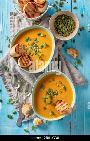 Cremige Kürbissuppe als Herbstmahlzeit. Kürbissuppe mit Crostini und Samen. Stockfoto