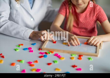 Entwicklungskurse Für Kinder. Nicht wiedererkennbares kleines Mädchen, das pädagogische Spiele während der psychologischen Beratung spielt Stockfoto