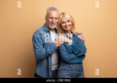 Ein gutaussehender, liebevoller, älterer Mann, der seine wunderschöne blonde Frau umarmt Stockfoto