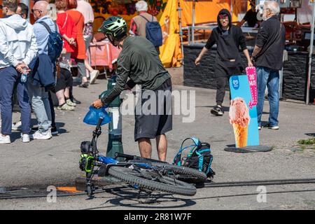 Mann mit einem Fahrradhelm, der einen Wasserbeutel aus einem öffentlichen Trinkbrunnen am Marktplatz in Helsinki, Finnland, füllt Stockfoto