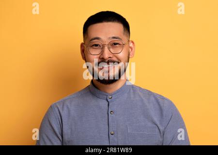 Porträt Eines Gutaussehenden Jungen Asiaten Mit Brille, Der Vor Gelbem Hintergrund Posiert Stockfoto