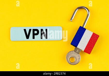 Auf einer gelben Oberfläche ein offenes Schloss mit dem Bild der französischen Flagge und einem Aufkleber mit der Aufschrift „VPN“ Stockfoto