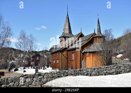 Ein altes Gebäude der Kirche Hol Gamle Kyrkje steht auf dem Land, in der Nähe einer gewundenen Straße Stockfoto