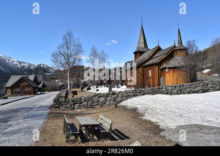 Ein altes Gebäude der Kirche Hol Gamle Kyrkje steht auf dem Land, in der Nähe einer gewundenen Straße Stockfoto