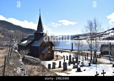 Ein altes Gebäude der Kirche Hol Gamle Kyrkje steht auf dem Land, in der Nähe einer gewundenen Straße Stockfoto