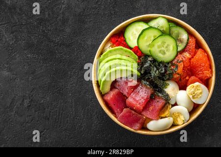 Schüssel mit Thunfisch, Avocado, Grapefruit, Eiern und Gurken auf schwarzem Hintergrund. Draufsicht Stockfoto