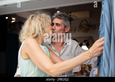 Elegante, bezaubernde, grauhaarige Frau, die ihren Mann beim Einkaufen küsst Stockfoto