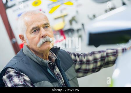 Porträt eines Mechanikers, der ein Fahrzeug inspiziert Stockfoto