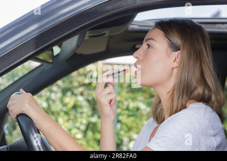 Frau setzen auf Lippenstift in einem Auto Stockfoto