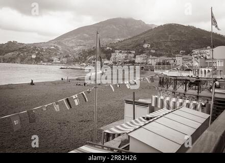 Riomaggiore Italien - 24 2011. April; im altmodischen Stil verblichenes Bild am Strand von Riomaggiore mit Gebäuden am Strand, Flaggen und umliegenden Hügeln Stockfoto