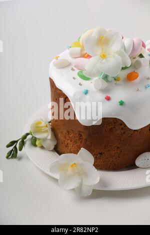 Traditioneller Osterkuchen mit Streuseln, Jelly Beans, Marshmallows, Blumen und dekoriertem Ei auf weißem Tisch, Nahaufnahme Stockfoto