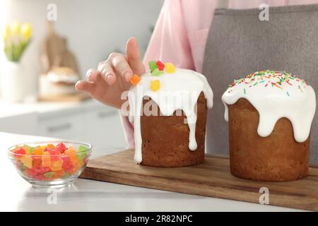 Eine Frau, die köstlichen Osterkuchen mit kandierten Früchten dekoriert, an einem weißen Marmortisch in der Küche, Nahaufnahme Stockfoto