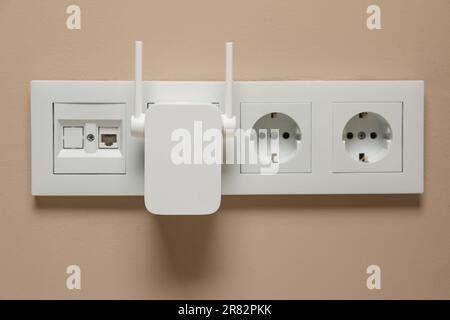 Drahtloser WLAN-Repeater in Steckdose an beiger Wand Stockfoto