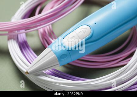 Eleganter 3D-Stift und farbenfrohe Kunststofffilamente auf Khaki-Hintergrund, Nahaufnahme Stockfoto