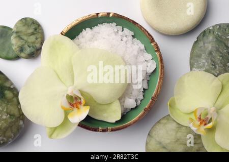 Flache Liegezusammensetzung mit Steinen, Spa-Produkten und wunderschönen Blumen auf weißem Tisch Stockfoto