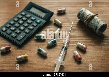 Medizinische Spesen-Konzept. Taschenrechner, verschüttete Pillen, Spritze und Banknoten. Stockfoto