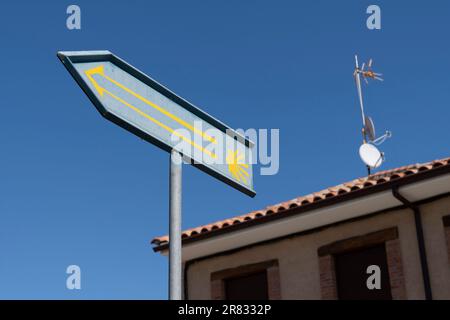 Ein modernes Schild mit Muschelmuschel führt Pilger entlang der Camino Frances im Dorf Santibáñez de Valdeiglesias in Leon, Spanien. Die Jakobsmuschel Stockfoto