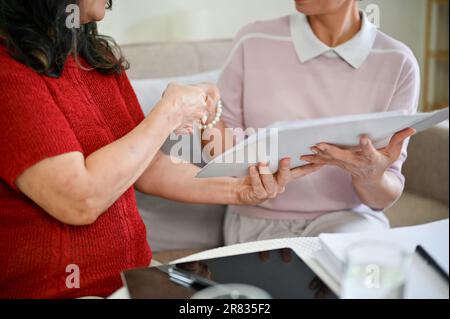 Nahaufnahme einer professionellen asiatischen Krankenversicherungskraft mittleren Alters schüttelt sich nach Abschluss einer Versicherung die Hand mit ihrem Klienten Stockfoto