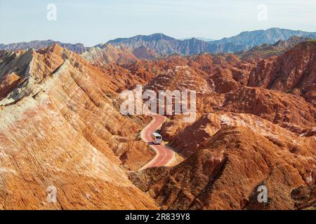 Kurvige Straße durch die bunten Regenbogenberge. Die chinesische Landschaft auf der Seidenstraße. Wunderschöner Sonnenuntergang im Zhangye Danxia National Geological Park, Gan Stockfoto