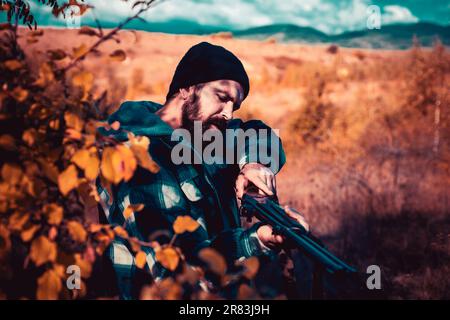 Jäger mit Schrotflinte auf der Jagd. Herbstjagd. Jagdsaison geschlossen und geöffnet. Wilderer im Wald. Bergjagd. Stockfoto