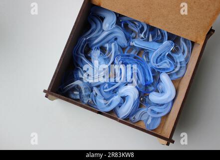 Plywood box with open lid half filled with translucent blue artificial crystal stones Stockfoto
