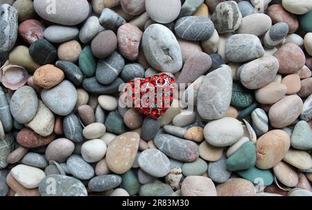 Heart shaped jewelry with red gemstones on a round sea pebbles Stock Photo