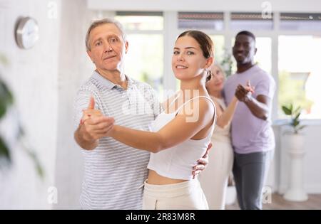 Junge Frau, die eine Gruppe multiethnischer Erwachsener unterrichtet. Sozialtanz Stockfoto