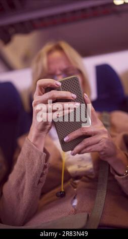 Nahaufnahme der Hände einer erwachsenen Frau mit einem Smartphone während der Fahrt mit dem Zug, Soft Focus Stockfoto