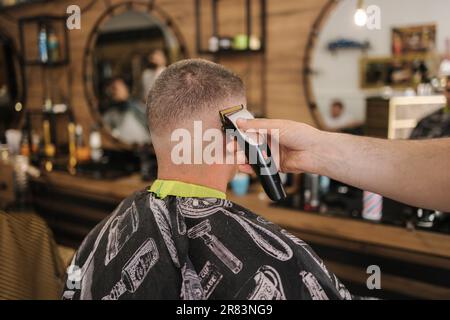Rückansicht eines Friseursalons, der dem männlichen Klienten Haare schneidet. Friseursalon Stockfoto