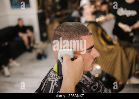 Ein gutaussehender Mann mit Haarschnitt im Friseur sitzt auf einem Stuhl. Stockfoto