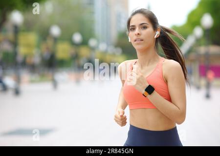 Läufer, die Ohrstöpsel und Smartwatch tragen und auf der Straße Musik hören Stockfoto
