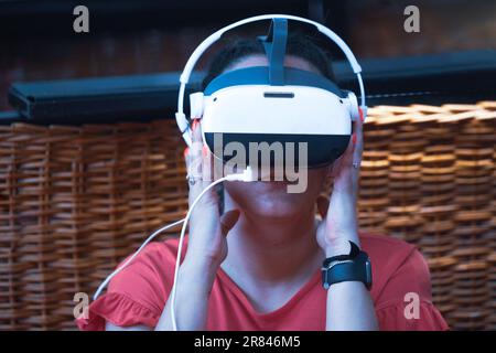 Rimini, Italien - 15. Juni 2023: Metaverse Digital Virtual Reality Technology of a Woman with Brillen and a Headset VR connected to the Virtual Space Stockfoto